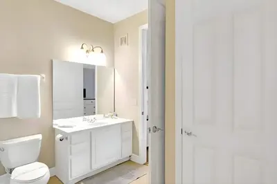 a white bathroom with a toilet and a sink at Updated 3BR Condo near Convention Center & Epic in Orlando