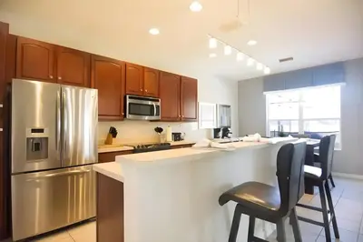 a kitchen with a counter and a stainless steel refrigerator at Free Water Park 4BR wPool Game Room 7739TB in Orlando
