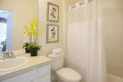 a white bathroom with a toilet and a sink at Free Water Park 4BR wPool Game Room 7739TB in Orlando