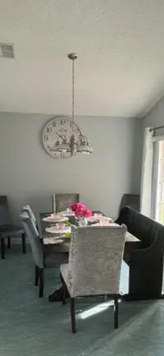 a dining room with a table and chairs and a clock at Family Dream Home Near Disney in Kissimmee