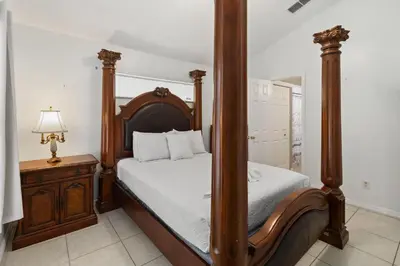 a bedroom with a four poster bed and a table at Cozy Home Near Disney!!! in Kissimmee