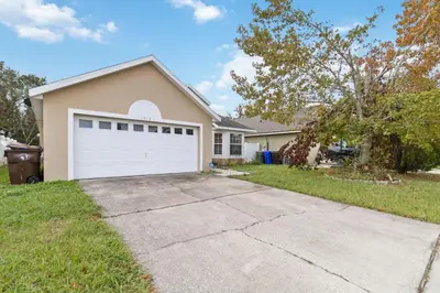 a house with a white garage door in a yard at Cozy Home Near Disney!!! in Kissimmee
