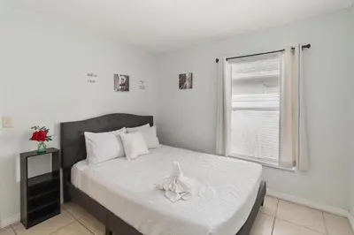 a bedroom with a bed with white sheets and a window at Cozy Home Near Disney!!! in Kissimmee