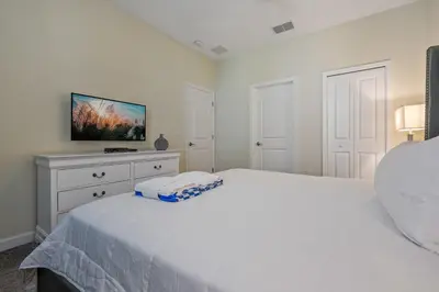 a bedroom with a white bed and a tv on a dresser at Storey Lake Resort 1120 - Hosted by Top Villas in Kissimmee