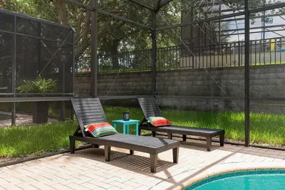 two lounge chairs sitting next to a swimming pool at Free Arcade! All Rooms Themed! South Facing Pool! in Orlando