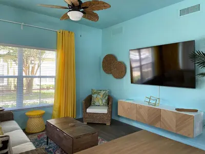 a living room with a flat screen tv on a blue wall at 4 Bedroom 3 Bathroom Villas At SevenDwarfs 27-108 in Kissimmee