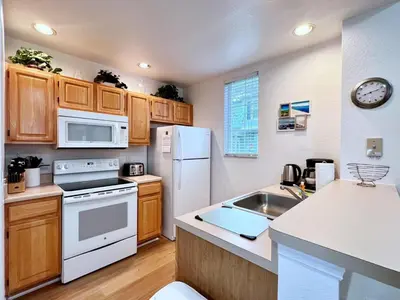 a kitchen with white appliances and wooden cabinets at Cute and Cozy 4Bed Townhome Venetian Bay-2200SCD in Kissimmee