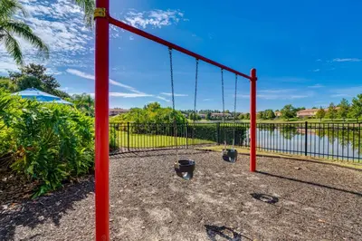 a swing set in front of a fence at 4 Mi to Disney World Townhome with Hot Tub and Lanai! in Kissimmee