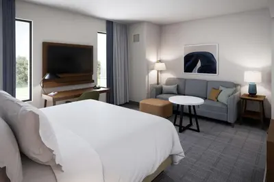 a hotel room with a bed and a couch and a television at Staybridge Suites Clermont Southeast by IHG in Clermont