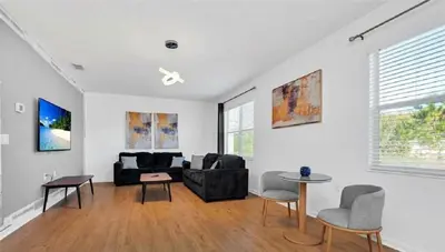 a living room with a black couch and a table at Disney Area Retreat 6BR4BA with Private Pool Theater Game Room Bella Vida Resort BV4509 in Kissimmee