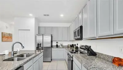 a kitchen with white cabinets and stainless steel appliances at Disney Area Retreat 6BR4BA with Private Pool Theater Game Room Bella Vida Resort BV4509 in Kissimmee