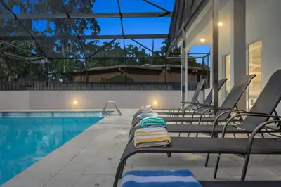 a row of lounge chairs next to a swimming pool at Luxury Ranch Master King Bed with heated Salted Pool in Orlando