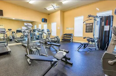 a gym with several treadmills and cardio machines at 3 Bedroom 2 Bathroom Villas At SevenDwarfs 8-103 in Kissimmee
