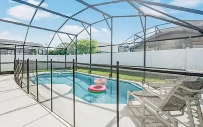 a house with a swimming pool and a patio at Enchanted Disney Vacation Villa in Kissimmee