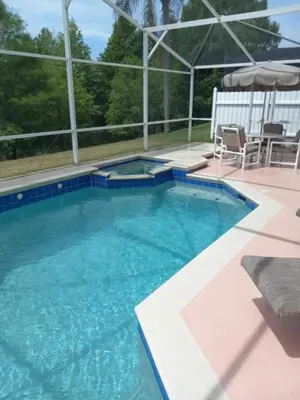 a large swimming pool with a table and an umbrella at Fabulous 4 Bed South Facing Lake View Near Disney in Orlando