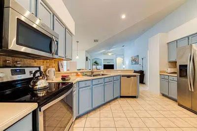 a large kitchen with blue cabinets and appliances at Spacious 4 Bed South Facing Pool Villa Near Disney in Orlando