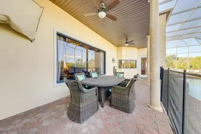 a patio with a table and chairs and a ceiling fan at Spacious 7 Bedroom Home Close To Disney in Orlando