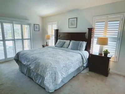 a bedroom with a large bed and two windows at Hidden Waterfront Oasis - 18 Minutes To The Disney in Orlando