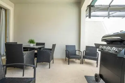 a patio with a table and chairs and a grill at Storey Lake Home Mickey & Minions Beds Sleeps 12 in Kissimmee