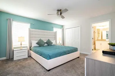 a bedroom with a bed and a blue wall at Storey Lake Home Mickey & Minions Beds Sleeps 12 in Kissimmee