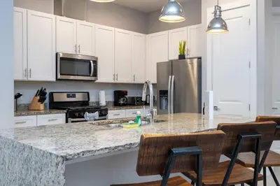 a kitchen with white cabinets and a granite counter top at Modern Chic Home Mickey and Toy Story Rooms in Orlando