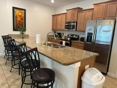 a kitchen with a refrigerator and a counter with bar stools at Home 4Bed in Storey Lake with Private Pool in Kissimmee