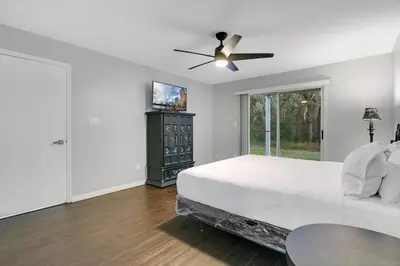 a white bedroom with a bed and a ceiling fan at Familiar Retreat with Resort Access Near Disney in Kissimmee
