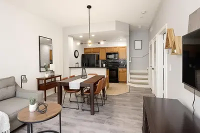 a living room and kitchen with a table and a couch at Disney-Area 3BR Townhome | Sleeps 9 | Pool + Gym in Kissimmee