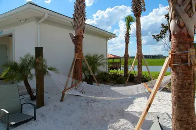 a hammock in front of a house with palm trees at Chic 2Bed Condo at Storey Lake Mickey Room in Kissimmee
