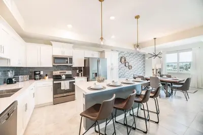 a kitchen with white cabinets and a blue island with chairs at Chic 2Bed Condo at Storey Lake Mickey Room in Kissimmee