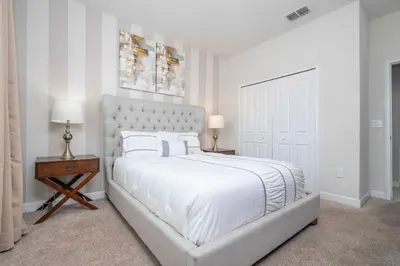 a white bedroom with a large bed with white sheets and pillows at Home 6Bed , Themed Rooms, Game Room, Storey Lake in Kissimmee