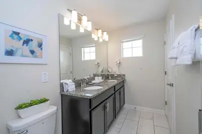 a bathroom with a sink and a toilet and a mirror at Home 6Bed , Themed Rooms, Game Room, Storey Lake in Kissimmee