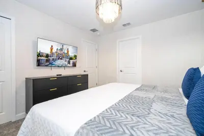 a bedroom with a bed and a tv on the wall at The Ultimate 9bd Disney Getaway Storey Lake in Kissimmee