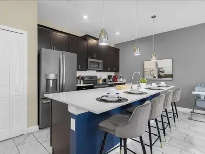 a kitchen with a large island with bar chairs at Comfortable 4 Bedrooms at Storey Lake in Kissimmee
