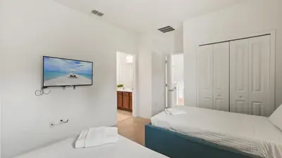 a bedroom with two beds and a tv on the wall at Summer Sale - Beautiful 6BR Home with Private Pool! in Kissimmee
