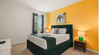 a bedroom with a large bed with an orange wall at Summer Sale - Beautiful 6BR Home with Private Pool! in Kissimmee