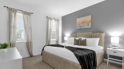 a bedroom with a large bed and two windows at Summer Getaway in FL - 6BR Home with Private Pool! in Kissimmee
