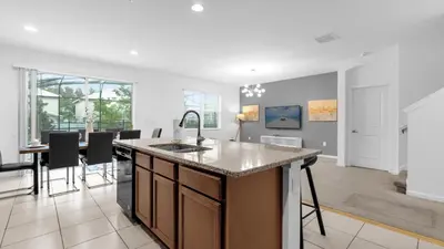an open kitchen and dining room with a large island at Summer Getaway in FL - 6BR Home with Private Pool! in Kissimmee