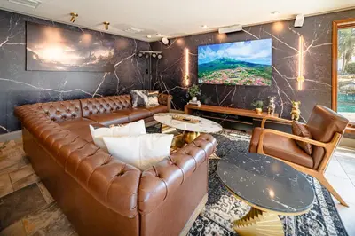 a living room with a leather couch and a tv at Luxury Lakefront 100,000 Gal Pool Villa - Orlando in Orlando