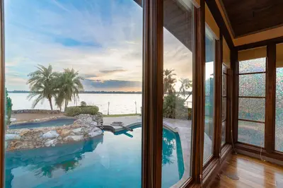 a house with a swimming pool with a view of the water at Luxury Lakefront 100,000 Gal Pool Villa - Orlando in Orlando