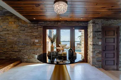 a dining room with a stone wall and a chandelier at Luxury Lakefront 100,000 Gal Pool Villa - Orlando in Orlando