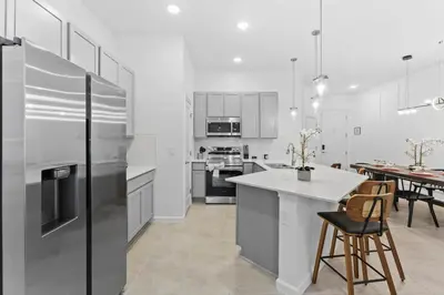 a kitchen with white cabinets and a table and chairs at Lux 5BR Home, Game Room, 4 Suites & Private Pool in Orlando