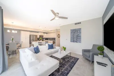 a living room with white furniture and a kitchen at 3111-102RD CONDO 2 BEDS/2 BATHS (SANITIZED) in Kissimmee