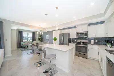a kitchen with white cabinets and a table and chairs at 3111-102RD CONDO 2 BEDS/2 BATHS (SANITIZED) in Kissimmee
