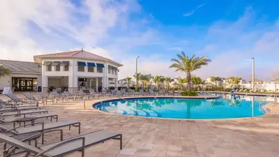 a swimming pool with chairs and a building at 2585LA TOWNHOUSE 4 BEDROOMS & 3 BATHROOMS + POOL in Kissimmee