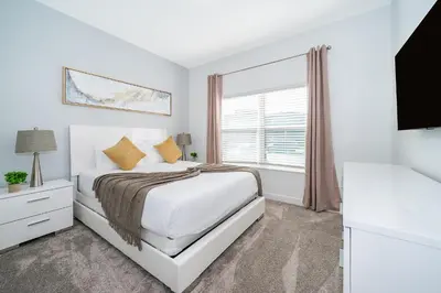 a white bedroom with a bed and a window at 4415RH TOWNHOUSE 5 BEDROOMS & 4 BATHROOMS + POOL in Kissimmee