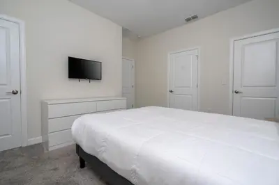 a white bedroom with a bed and a flat screen tv at 4337 QS - Charming Hideaway in Kissimmee