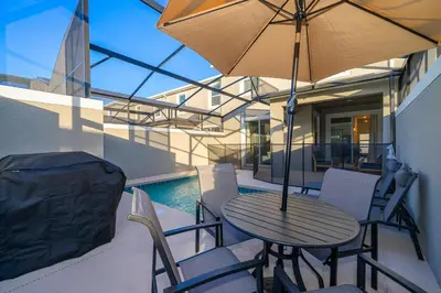 a table and chairs with an umbrella on a patio at 4220AA TOWNHOUSE 4 BEDROOM 3 BATHS + PRIVATE POOL in Kissimmee