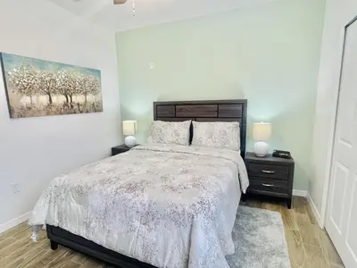 a bedroom with a bed and a painting on the wall at Cozy Condo Minutes Away From Disney in Kissimmee