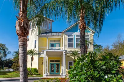 a yellow house with palm trees in front of it at Barefoot'n Resort Kissimmee Orlando in Orlando
